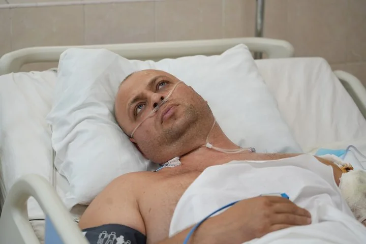 Чоловік у лікарняному ліжку з кисневою канюлею дивиться вгору