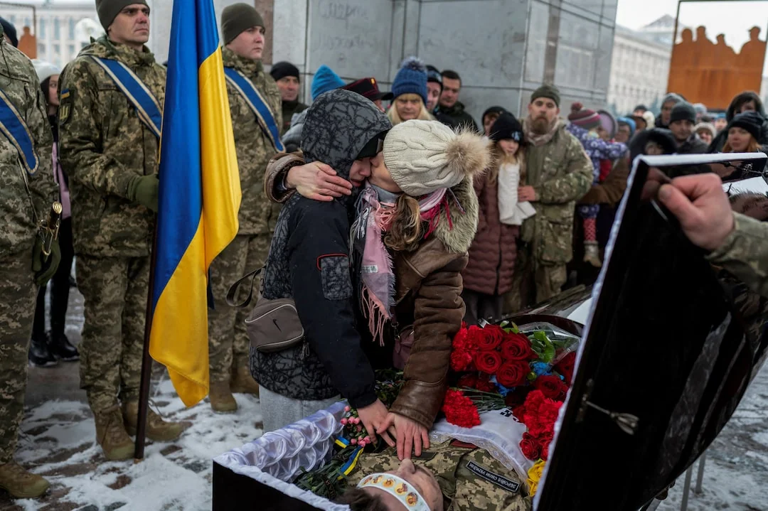 Люди зі свічками біля цинкового гробу військового на похованні